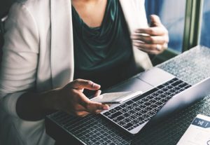 lady with laptop holding phone